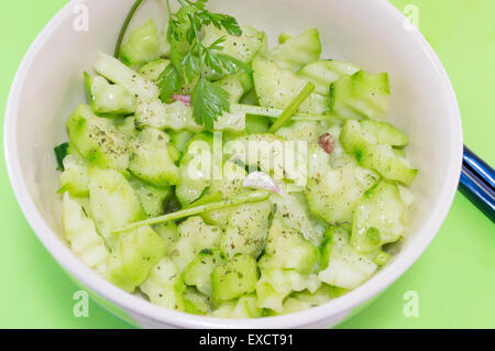 Avec salade de concombre et d'oignon persil avec des courges à côté de baguettes japonaises sur fond vert servi Banque D'Images