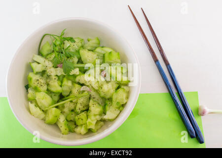 Salade avec des courges et cucamber avec oignon persil à côté de baguettes japonaises sur fond vert servi Banque D'Images