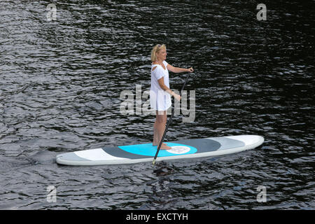 Blonde woman paddling une pagaie sangliers sur le lac Long New York USA US Banque D'Images