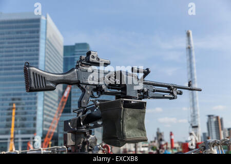 Objectif général de mitrailleuse dans l'accent sur le pont d'un navire du flou des immeubles modernes et des grues à Londres n'est pas mise au point Banque D'Images