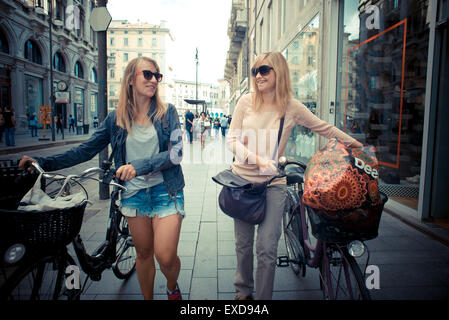 Deux belles femmes blondes shopping sur le vélo dans la ville Banque D'Images