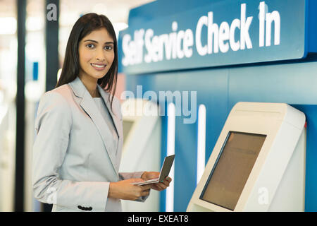 Gorgeous Indian businesswoman using self help vérifier dans la machine à l'aéroport Banque D'Images