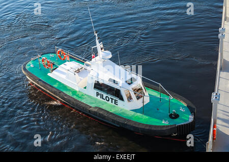 Petit bateau avec pilote de pont vert et noir de l'eau de mer sur une coque Banque D'Images