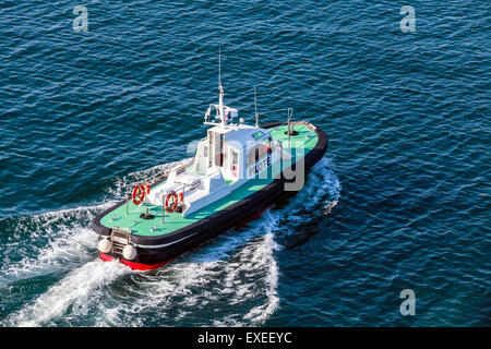 Petit bateau avec pilote de pont vert et noir coque est en cours sur l'eau de mer Banque D'Images