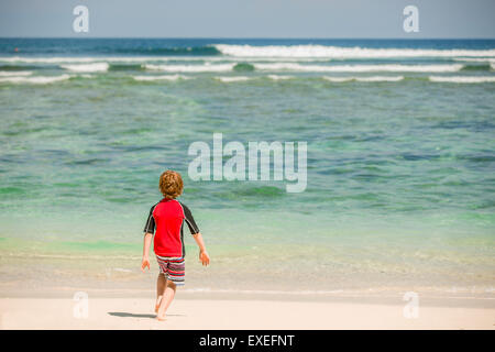 7 ans garçon mignon dans rushwest rouge maillot de bain à la plage tropicale de sable blanc et de l'océan vert