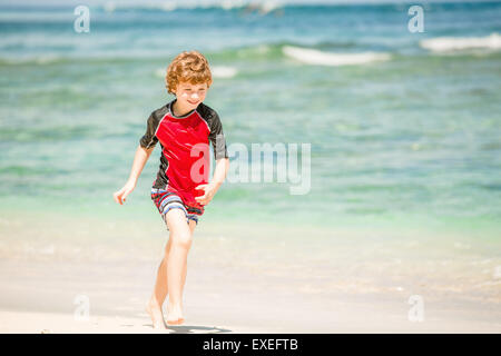 7 ans garçon mignon dans rushwest enjoing rouge maillot de l'heure d'été à la plage tropicale de sable blanc et de l'océan vert