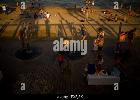 Les gens cool dans les douches et la mer à la plage de Barcelone au coucher du soleil le 10 juillet, 2015. Banque D'Images