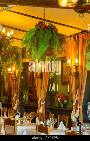 Tables de restaurant avec l'argenterie et des verres prêts pour un déjeuner ou dîner dans un jardin Banque D'Images