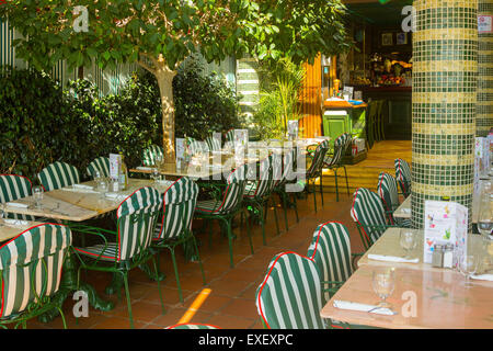 Tables de restaurant avec l'argenterie et des verres prêts pour un déjeuner ou dîner dans un jardin Banque D'Images