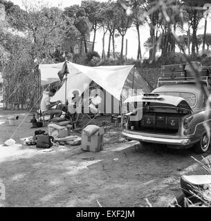 Cette image montre des campeurs avec leur voiture, probablement prise au milieu du XXe siècle. Il capture l'essence d'une forme populaire de loisirs en plein air pendant cette période, où les familles ou les groupes de voyageurs utilisaient des voitures pour explorer la nature et camper dans des endroits éloignés. Banque D'Images