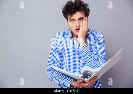 Jeune homme choqué avec commandes de documents et dossiers looking at camera Banque D'Images