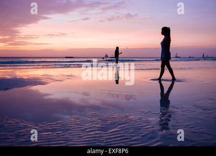 La silhouette du jeune femme se promenant sur la plage au coucher du soleil, l'île de Boracay, Visayas, Philippines Banque D'Images