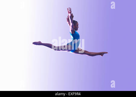 Jeune gymnaste à la mi-air leap Banque D'Images