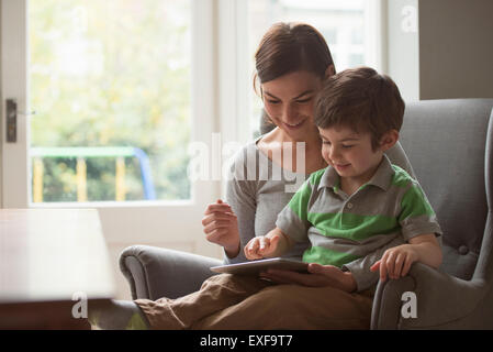 Garçon assis sur les genoux de sa mère et using digital tablet Banque D'Images