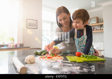 Mère et fils la préparation de pizza together in kitchen Banque D'Images