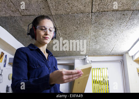 Young female carpenter examinant en bois atelier Banque D'Images