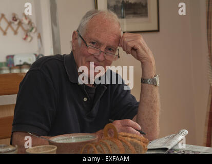 Portrait of senior man, assis à table de petit-déjeuner avec du papier journal Banque D'Images