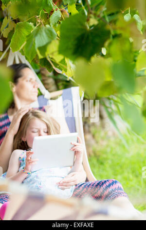 Fille assise sur les genoux de mère using digital tablet Banque D'Images