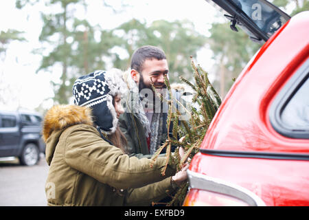 Jeune couple avec arbre de Noël en démarrage auto Banque D'Images