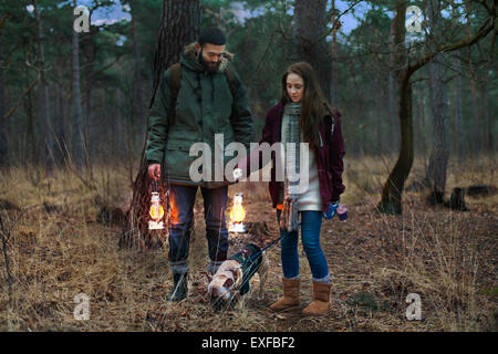 Jeune couple avec des lanternes randonnées à pied dans les bois de chien Banque D'Images