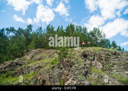 Garçon debout sur le haut de falaise rocheuse Banque D'Images