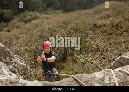 Male rock climber taking photo with smartphone Banque D'Images