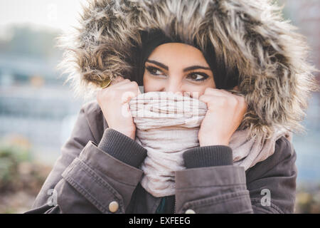 Close up of beautiful young woman in park holding up foulard en face de visage Banque D'Images