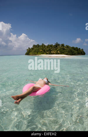 Mid adult woman flottant sur l'anneau de caoutchouc dans l'Océan Indien, les Maldives Banque D'Images
