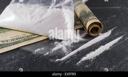 Grand sac et les lignes de la cocaïne sur une surface en verre avec un roulé one hundred dollar bill Banque D'Images