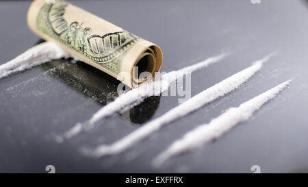Lignes de la cocaïne sur une surface en verre avec un roulé one hundred dollar bill Banque D'Images