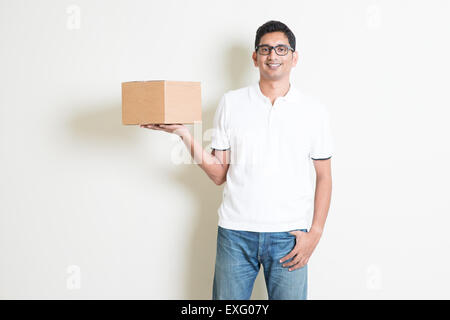 Indian man smiling, boîte de messagerie Livraison, debout sur fond uni avec l'ombre. Beau mec asiatique modèle. Banque D'Images