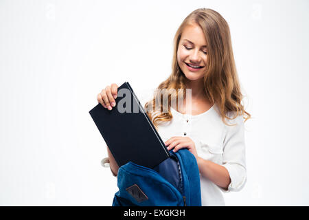 Happy young woman putting livre en sac à dos isolé sur fond blanc Banque D'Images
