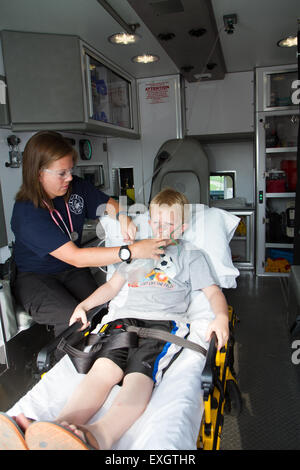 Female paramedic aider les jeunes patients de sexe masculin à l'arrière de l'ambulance. Banque D'Images