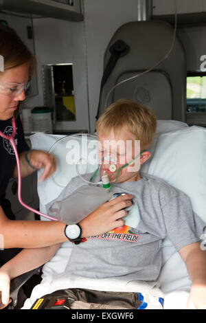 Female paramedic aider les jeunes patients de sexe masculin à l'arrière de l'ambulance. Banque D'Images