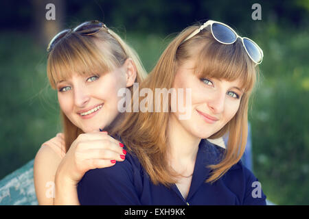Portrait de soeurs jumelles au parc. Deux jeunes belles filles à droite. Les tons de couleurs chaudes de droit Banque D'Images