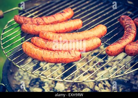 Vintage photo de savoureuse saucisse polonaise sur le gril en plein air. Banque D'Images