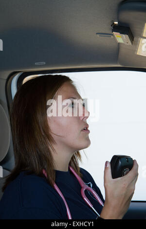 Female paramedic EMT en utilisant la radio en ambulance. Les pompiers volontaires d'ambulance. Banque D'Images