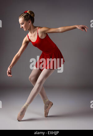 Belle femme ballerine sur fond gris. Ballerine est vêtu d'un justaucorps rouge, rose bas, les pointes et d'un red Banque D'Images