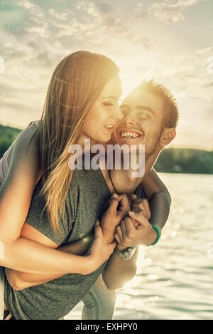 Couple in love embrassant au bord du lac, sun flare Banque D'Images