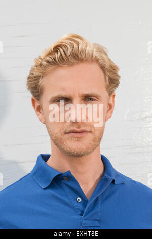 Portrait d'un homme blond avec des chaumes face portant un polo bleu. Banque D'Images