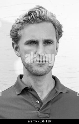 Portrait d'un homme blond avec le chaume portant un polo en noir et blanc. Banque D'Images