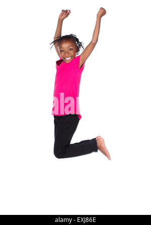 Adorable petit enfant africain avec tresses, portant un t-shirt vert et noir skinny jeans. La jeune fille saute et souriant. Banque D'Images