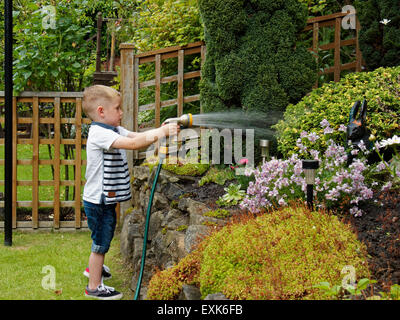 Tout-petit tuyau flexible d'arrosage avec des plantes de jardin Banque D'Images