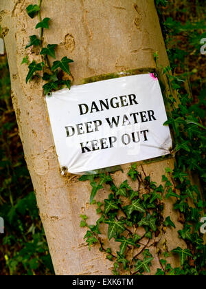 Tenir hors de l'eau profond Danger sign attaché à un tronc d'arbre avec ivy Banque D'Images