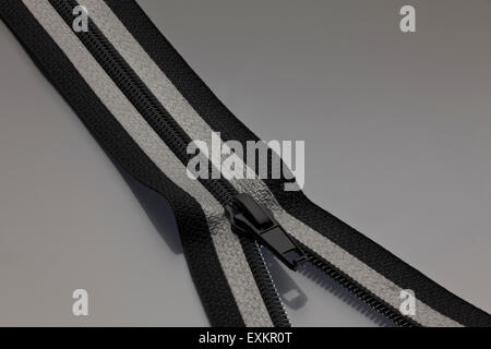 Fermeture éclair en noir et gris ouvert à une surface gris Banque D'Images