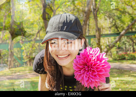 Happy Asian Thai jeune femme avec dahlia rose fleur qui s'épanouit dans le jardin Banque D'Images