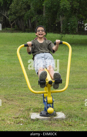 Thai asiatique teen smiling boy l'exercice sur les appareils de sport en jardin Banque D'Images