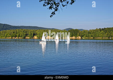 Trois yacht bateaux naviguant sur le lac de Solina dans le Parc National de Bieszczady, réflexions visible sur eau bleu clair.Sport et loisirs Banque D'Images