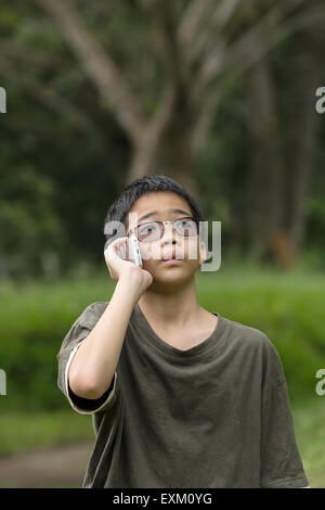 Thai asiatique jeune garçon talking on mobile phone piscine Banque D'Images