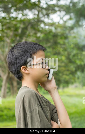 Thai asiatique jeune garçon talking on mobile phone piscine Banque D'Images